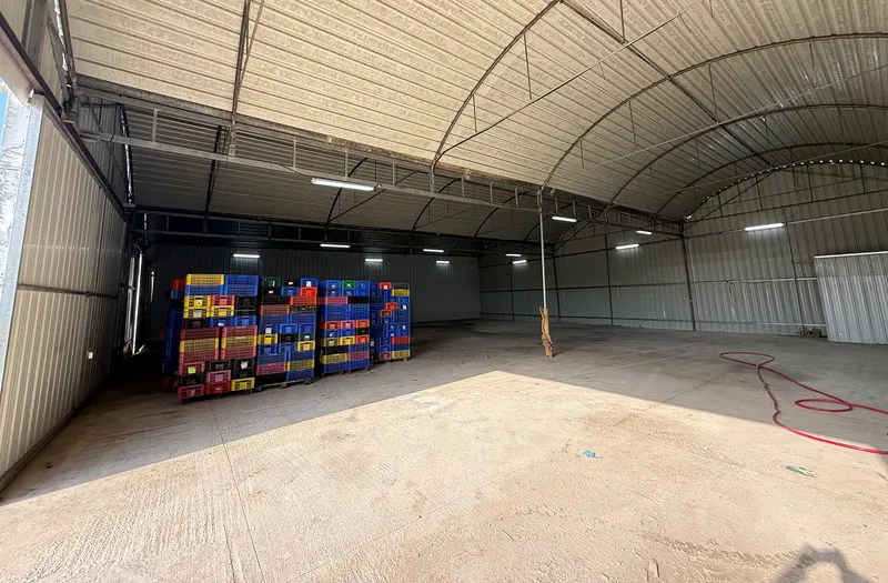 פנים המחסן: חלל פתוח ורחב עם רצפת בטון וגג קשתי